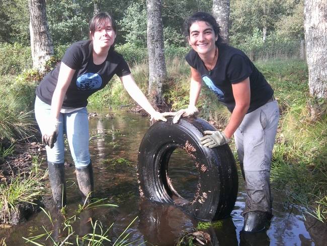 Dos voluntarias sacan un neumático de un río durante la VII Limpieza Simultánea de Ríos en Galicia (foto: Adega).
