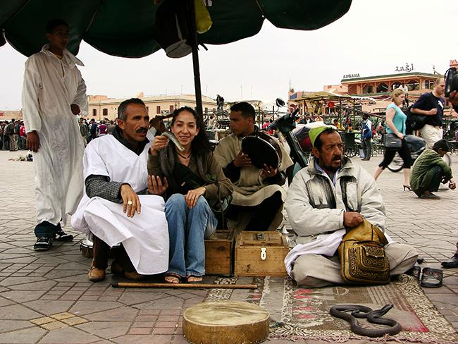 Encantadores de serpientes en la plaza Ymaa el Fna de Marrakech posando con una turista (foto: Mónica Feriche).